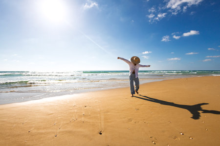 Woman on the beach. Happy young woman in a white shirt enjoying her vacation on the beach. Free lifestyle concept.の写真素材