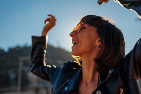 Girl dancing and enjoying music at a rock concert, stylish girl in a leather jacket dancing...