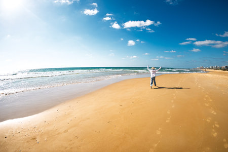 Woman on the beach. A young happy woman in flowing clothing walks along the seashore. The girl enjoys the walk and dances on the beach.の写真素材