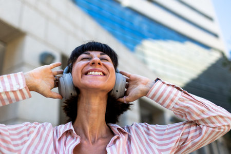 A charming young woman listens to music on headphones. A happy, relaxed girl enjoys her favorite song. Enjoy the music.の写真素材