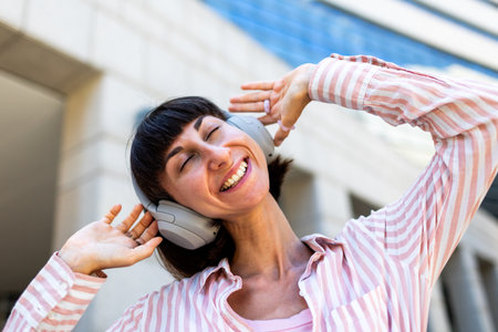 A charming young woman listens to music on headphones. A happy, relaxed girl enjoys her favorite song. Enjoy the music.の写真素材