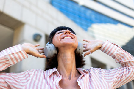A charming young woman listens to music on headphones. A happy, relaxed girl enjoys her favorite song. Enjoy the music.の写真素材