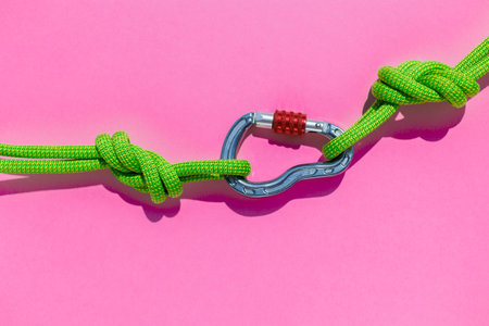 rope with a secure knot and a carabiner lies on a colored background. Equipment for rock climbing...