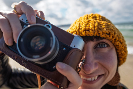 Woman taking photos outdoors. close-up of camera. Young beautiful girl creating content while walking on the beach. travel and vacation.の写真素材