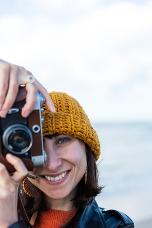 Young girl taking photo outdoors with film camera. Young girl tourist having fun on beach. Lifestyle portrait.の写真素材