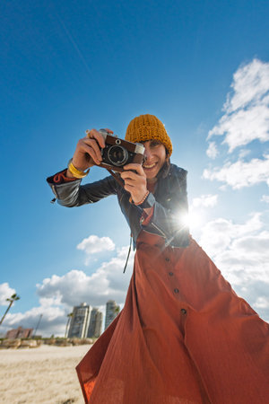 Woman taking photos outdoors. close-up of camera. Young beautiful girl creating content while walking on the beach. travel and vacation.の写真素材