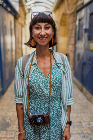 A female traveler enjoys a moment of vacation. The girl stands on a narrow street in a city. Travel blogger.の写真素材