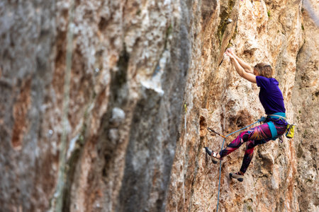 Climber overcomes challenging climbing route. Woman engaged in extreme sport. A girl climbs a rock. Extreme hobby.の写真素材