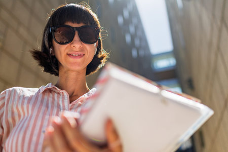 A woman stands on a sunny city street near a business center. A happy woman in the city.