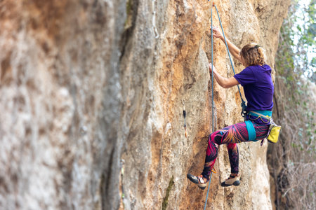 Climber overcomes challenging climbing route. Woman engaged in extreme sport. A girl climbs a rock. Extreme hobby.の写真素材