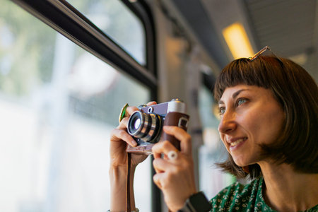 girl traveling by train and taking pictures. stylish girl with camera in hands enjoying the train...