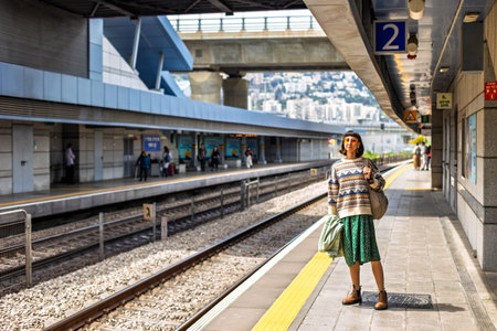 Stylish young girl with backpack standing on platform waiting for train. Travel and adventure.の写真素材