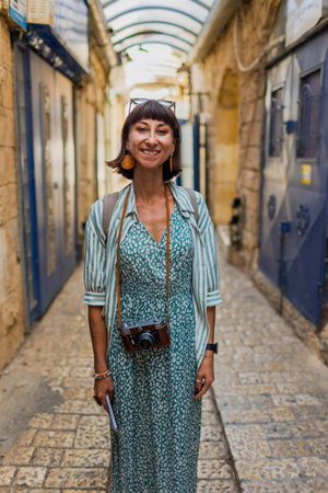 A girl with a camera stands on a narrow street in an Arab city. Travel blogger.の写真素材