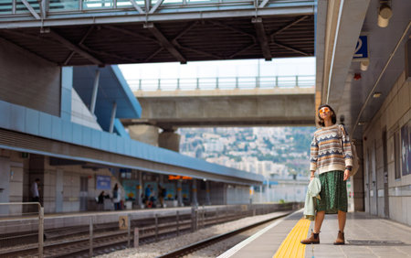 girl looking at watch and waiting for train. girl standing at train station waiting for train. freedom and travel concept.の写真素材