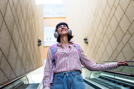 A young woman listens to music on headphones and enjoys her favorite song while walking around the city. Enjoy the music.の写真素材