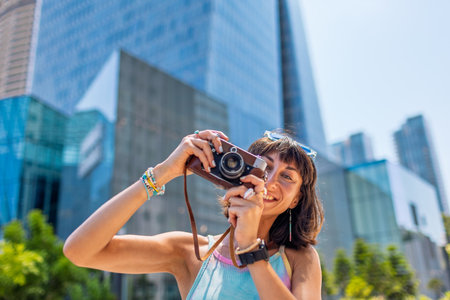 girl taking photo. Summer outdoor lifestyle, portrait of young beautiful woman having fun and enjoying vacation, traveling with camera. girl in city.の写真素材
