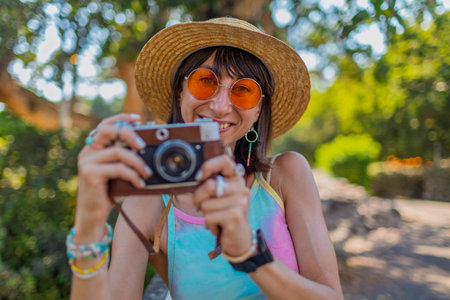Stylish woman with a camera on the street. Portrait of a beautiful girl smiling on the street. Stylish tourist with a film camera. Girl with a camera.の写真素材