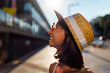 Portrait of smiling beautiful young woman wearing round fashionable sunglasses and straw hat. Close-up. Style and fashion.の写真素材