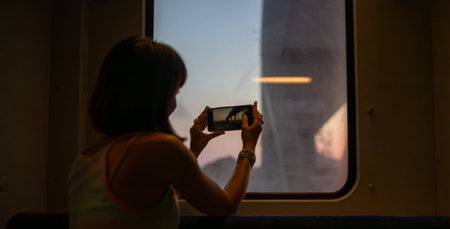 Young woman travels by train and creates content for social networks. Girl takes photos from the window of a moving train. Train travel.の写真素材