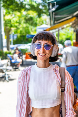 Young woman listening to music on headphones. Stylish girl listening to songs through wireless headphones. Girl in enjoying the song.の写真素材