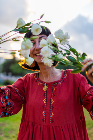 Romantic mood. Portrait of a young beautiful woman in a beautiful dress and with a bouquet of flowers at sunset. The girl smiles and looks at the camera.の写真素材