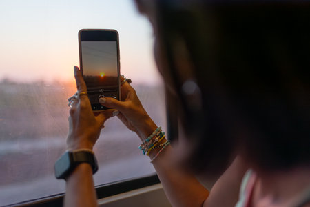 Young woman travels by train and creates content for social networks. Girl takes photos from the window of a moving train. Train travel.の写真素材