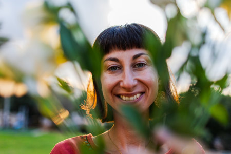 Romantic mood. Portrait of a young beautiful woman in a beautiful dress and with a bouquet of flowers at sunset. The girl smiles and looks at the camera.の写真素材