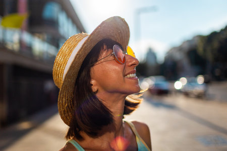Portrait of smiling beautiful young woman wearing round fashionable sunglasses and straw hat. Close-up. Style and fashion.の写真素材