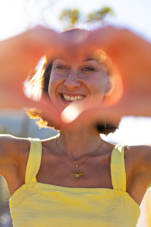 Smiling girl making love sign at sunset. romantic mood. Portrait of young smiling charming woman...