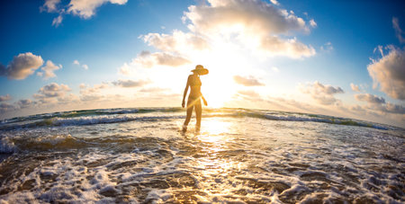 Slender girl having fun in the sea and her legs are washed by ocean waves. young girl on the beach....