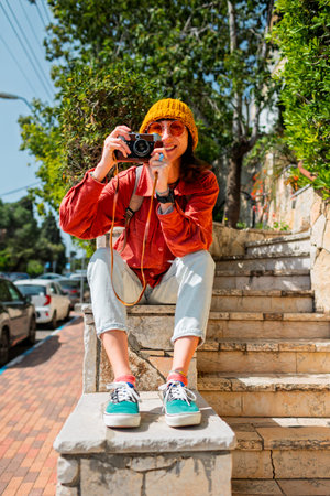 Stylish girl using camera. Urban style and fashion. Tourist with camera walking around the city....