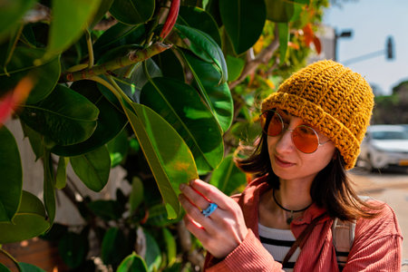 Happy girl touching leaf. Young woman smiling looking at wall covered with green leaves.