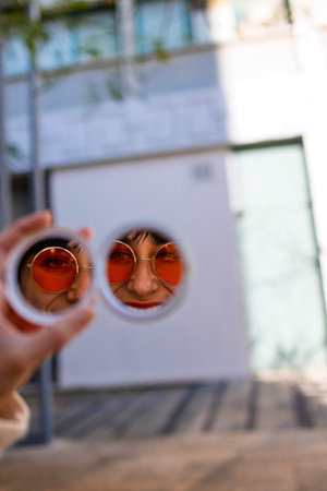 Woman using a cosmetic pocket mirror. Beautiful young woman looking at herself in a cosmetic pocket...