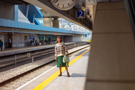 girl looking at watch and waiting for train. girl standing at train station waiting for train....