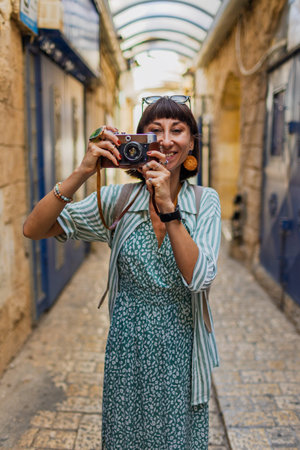 An attractive tourist with a camera. A beautiful woman with a camera takes pictures of beautiful places. The girl raises the camera to her face and takes a photo. Travel and adventure.の写真素材