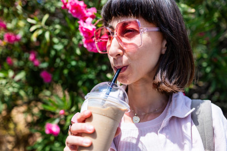 A woman enjoys her coffee and smiles. She's relaxing, taking a break. A young lady walks down the...