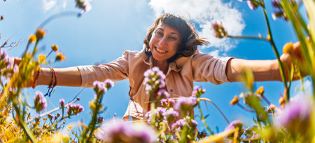 A happy girl. A woman picking wildflowers in a field. A girl in a meadow picking a bouquet of flowers on a summer day. Spending time outdoors in spring.の写真素材