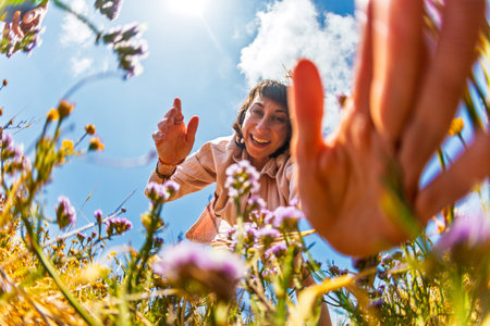 A happy girl. A young woman picks colorful flowers among lush greenery under a bright sky, enjoying the tranquility of nature. Flower picking.の写真素材