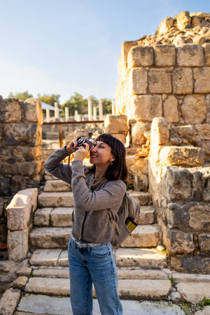 A stylish tourist with a backpack photographs landmarks for her blog and social media. A tourist...