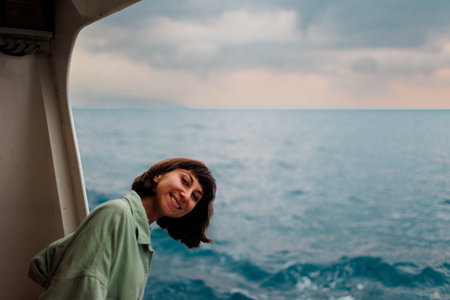 girl stands on the deck of a cruise ship. The girl is traveling. A young beautiful brunette travels on a yacht. travel and adventure.の写真素材