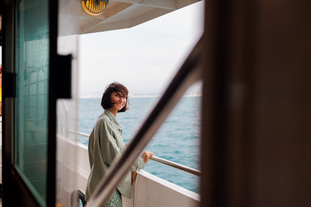 A young woman stands on the deck of a cruise ship and looks at the setting sun. A young beautiful...
