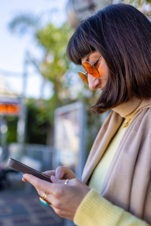 A young woman scrolls through her feed while waiting for a train. A passenger checks the train...