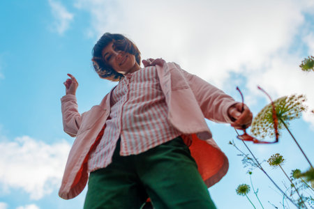 Photo of a girl dancing in a flower field against the sky. minimalistic and simpleの写真素材