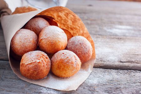 Freshly made donuts from cottage cheese with powdered sugar in a paper bag, copy spaceの写真素材