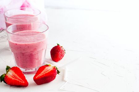 Strawberry milkshake in glass glasses on white table, copy space, horizontalの写真素材