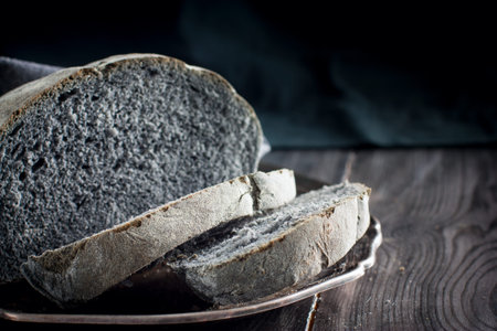 Homemade black coal bread on a wooden table, horizontal, copy space