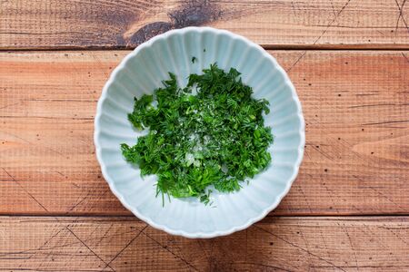 Step-by-step preparation of traditional Russian cold okrosh soup, step 2 chopping greens and adding salt, top view, horizontalの写真素材