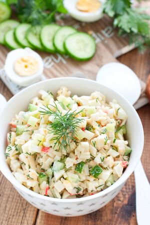 Salad with crab sticks, fresh cucumbers and rice in a white bowl, selective focusの写真素材