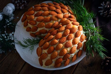 Puff salad made in the form of cones with almonds on a festive table, selective focusの写真素材