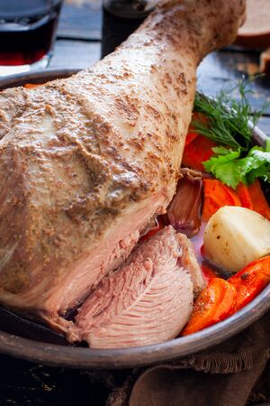 Baked turkey drumstick in a bowl, with a cut piece on a wooden table, selective focusの写真素材